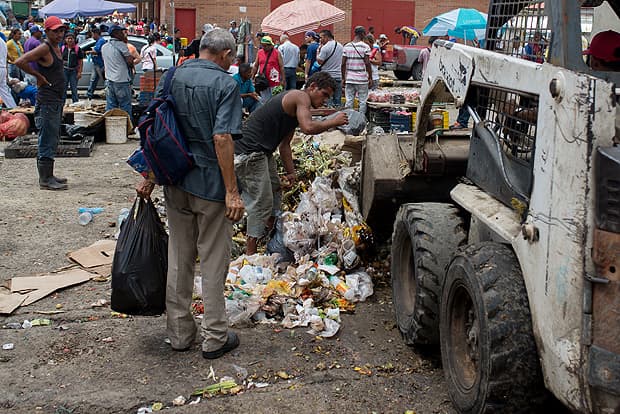 FOTO - DESESPERADOR: Venezuelanos disputam comida com cães no lixo de feira em Caracas; taxa de pobreza em 76%