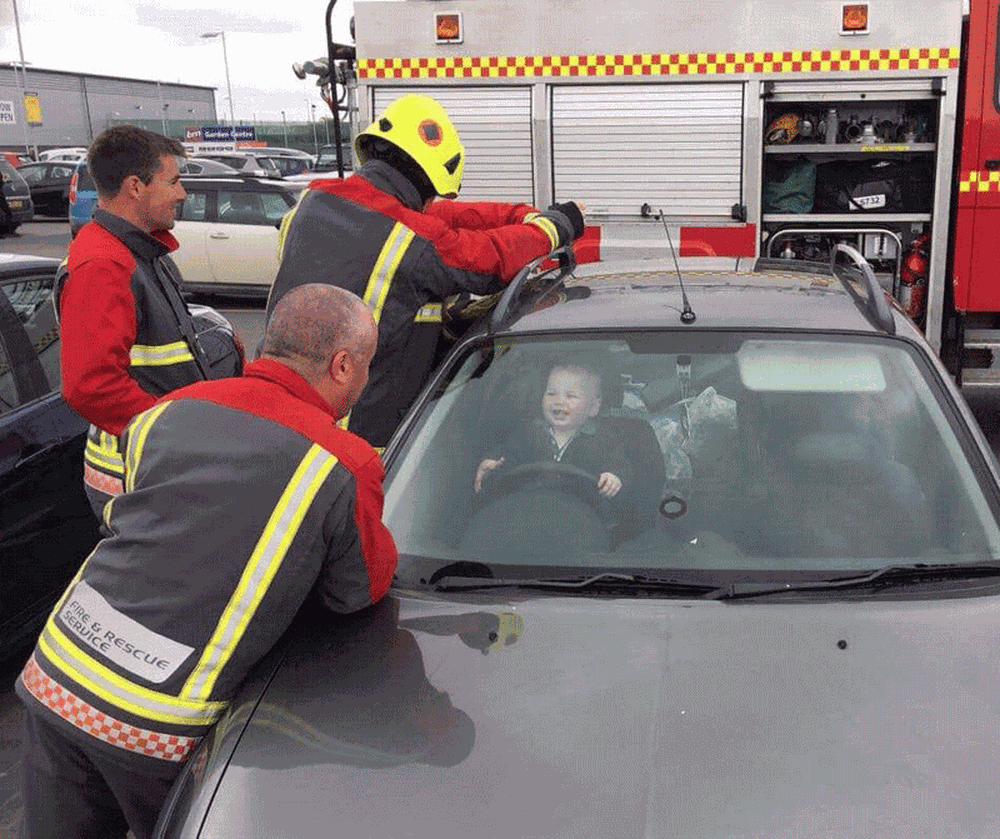 (FOTO) COM POTENCIAL DE VIRAL: Bebê tranca-se acidentalmente em carro e ri de bombeiros que o salvaram