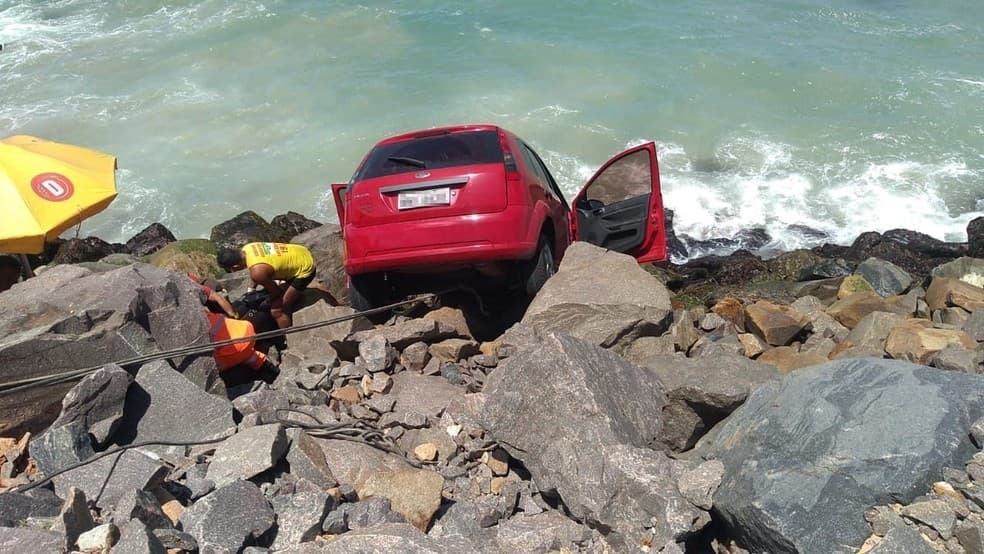 FOTOS: Carro cai sobre pedras e fica pendurado próximo ao mar em Natal; motorista é resgatada pelos bombeiros